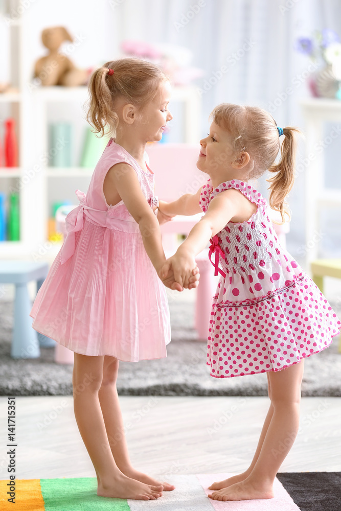 Cheerful little girls dancing at home