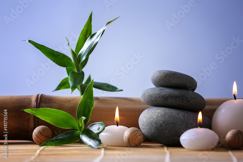 Spa stones with candles on color background