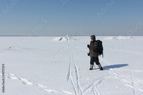 Nordic Walking - adult man with a backpack hiking on snow in winter