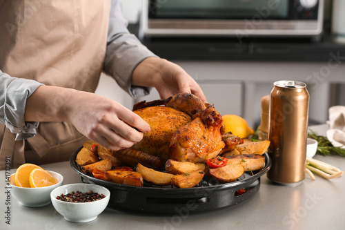 Woman with grilled beer can chicken on table