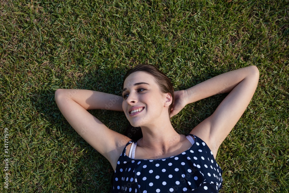 Smiling woman lying on grass with hands behind head Smiling woman lying on grass with hands behind head