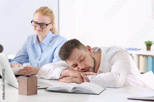 Tired young man sleeping during conference in office