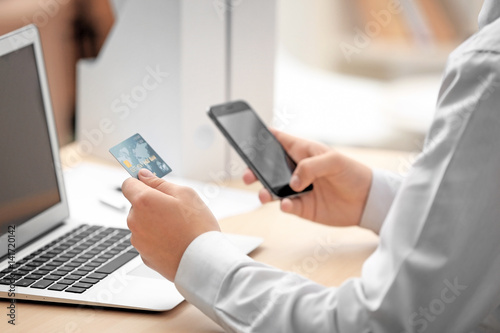Man sitting in office with credit card and mobile phone