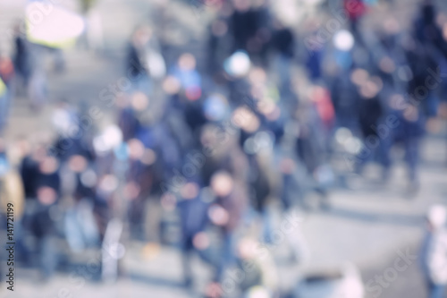 Crowd of people walking on busy city street, blurred view