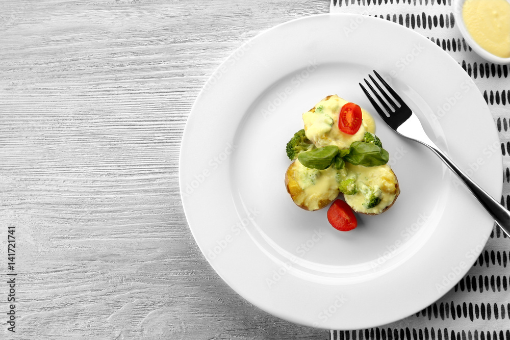 Plate of delicious baked potato with cheese sauce on white wooden background Plate of delicious baked potato with cheese sauce on white wooden background