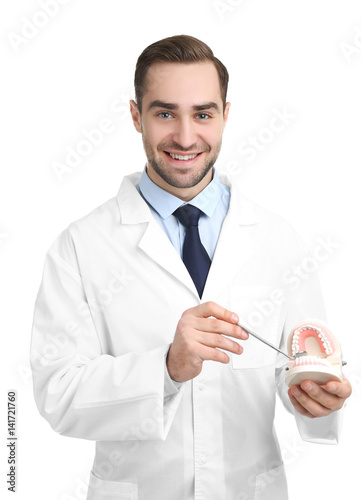 Handsome young dentist with jaw model and mirror on white background