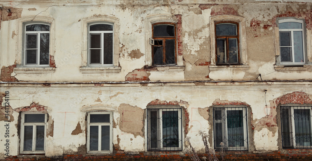 Background, texture, an old abandoned building. Wall with crumbling plaster and paint, Windows