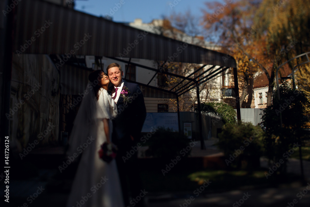Shadows hide beautiful newlyweds hugging on the backyard Shadows hide beautiful newlyweds hugging on the backyard