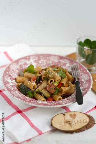 Pasta with flower sprouts and chorizo. White background, red plate, pilea.