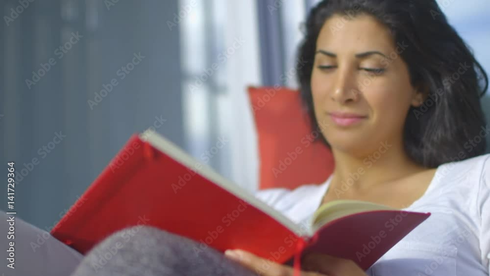 Head and Shoulder Worms eye view shot at a 25 degree angle of a woman sitting on the couch outside writing on her diary. The diary is in focus. Head and Shoulder Worms eye view shot at a 25 degree angle of a woman sitting on the couch outside writing on her diary. The diary is in focus.