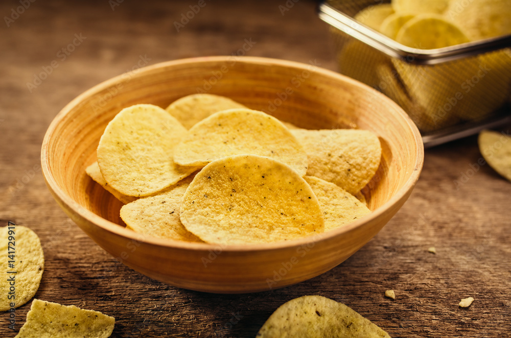 Crispy potato chips in bowl on wooden background. Closeup. Food background Crispy potato chips in bowl on wooden background. Closeup. Food background