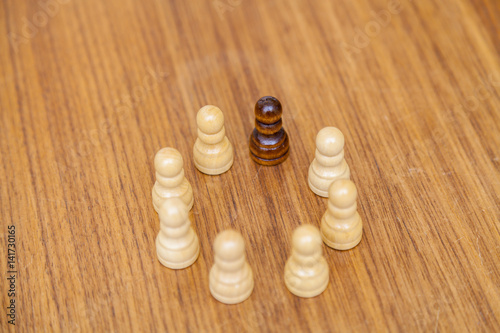 Wei  e Schachfiguren und eine schwarze im Kreis angeordnet. Symbol f  r Inklusion und Miteinander