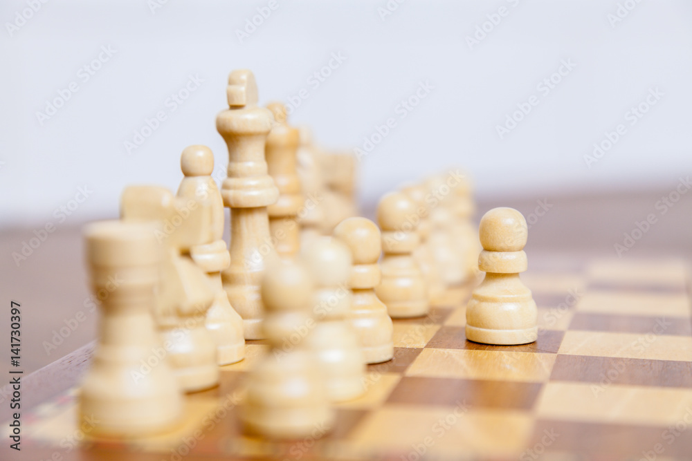 Weiße Schachfiguren auf einem Schachbrett in Ausgangsstellung, weißer Bauer hat den ersten Weiße Schachfiguren auf einem Schachbrett in Ausgangsstellung, weißer Bauer hat den ersten