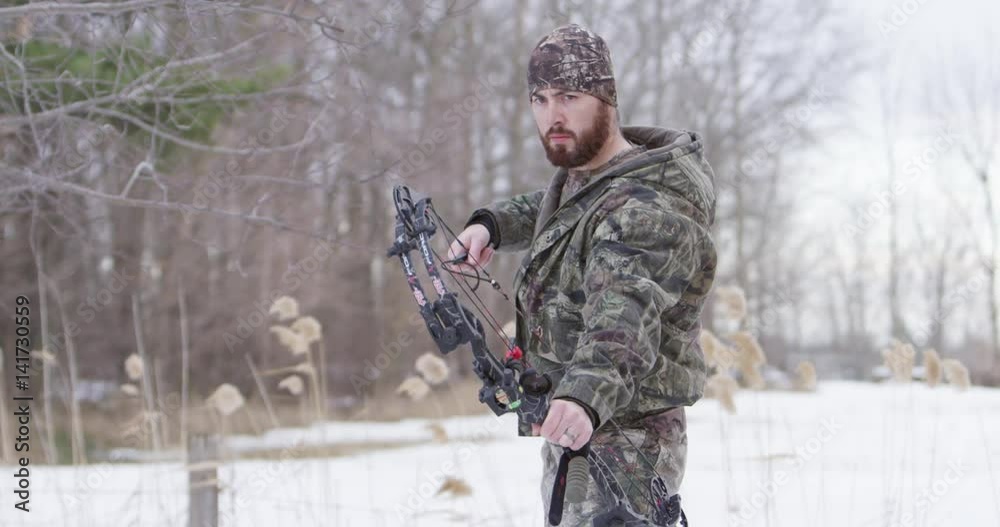 bow hunter shoots while winter snow flakes fall 4k