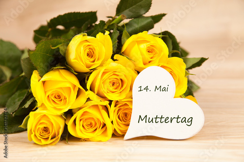 gelbe Rosen auf einem Holzhintergrund mit Text 14. Mai Muttertag
