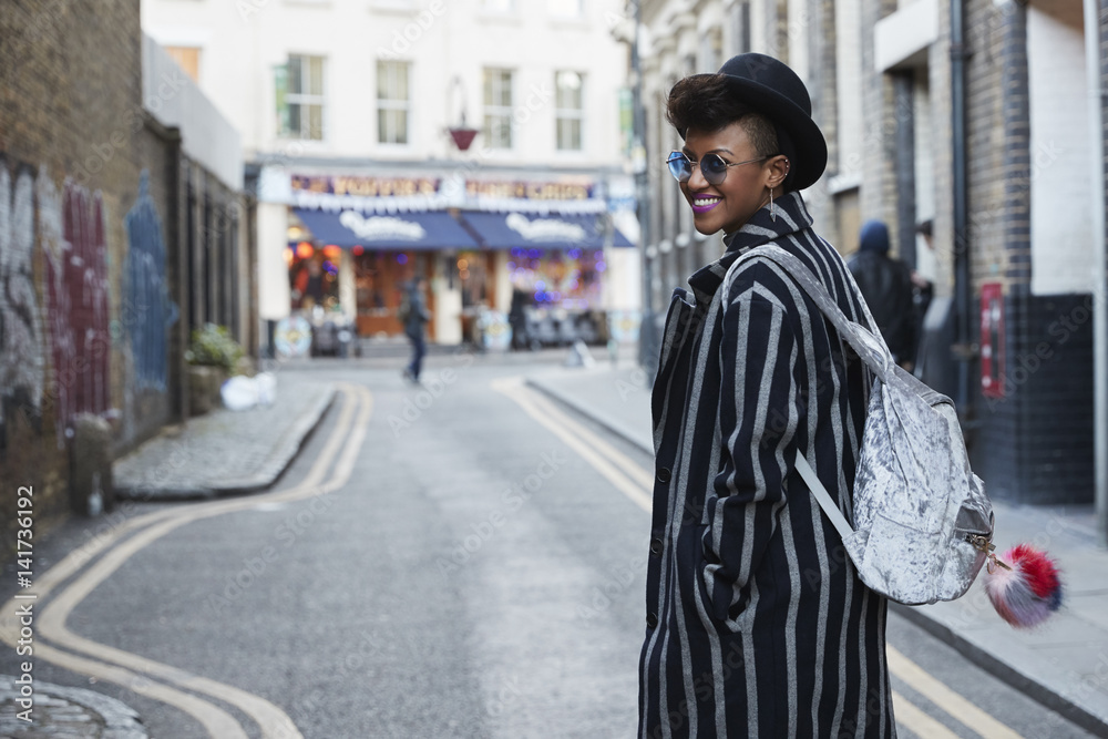Woman in striped coat and hat turns and smiles in the street Woman in striped coat and hat turns and smiles in the street