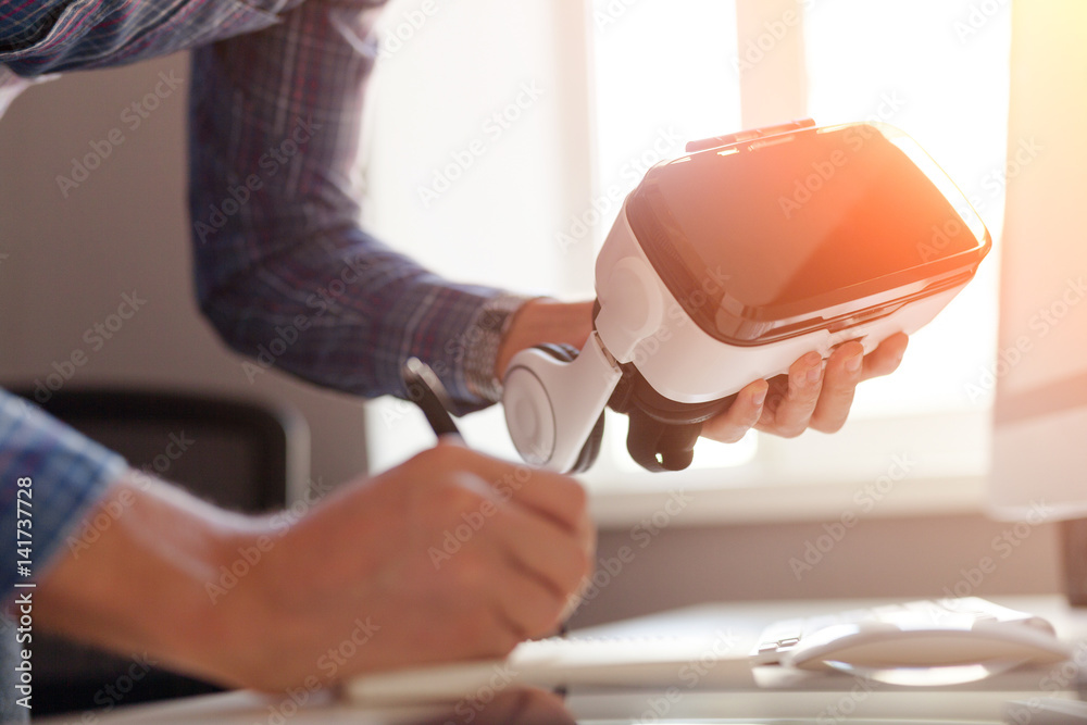 Man holding VR headset and writing