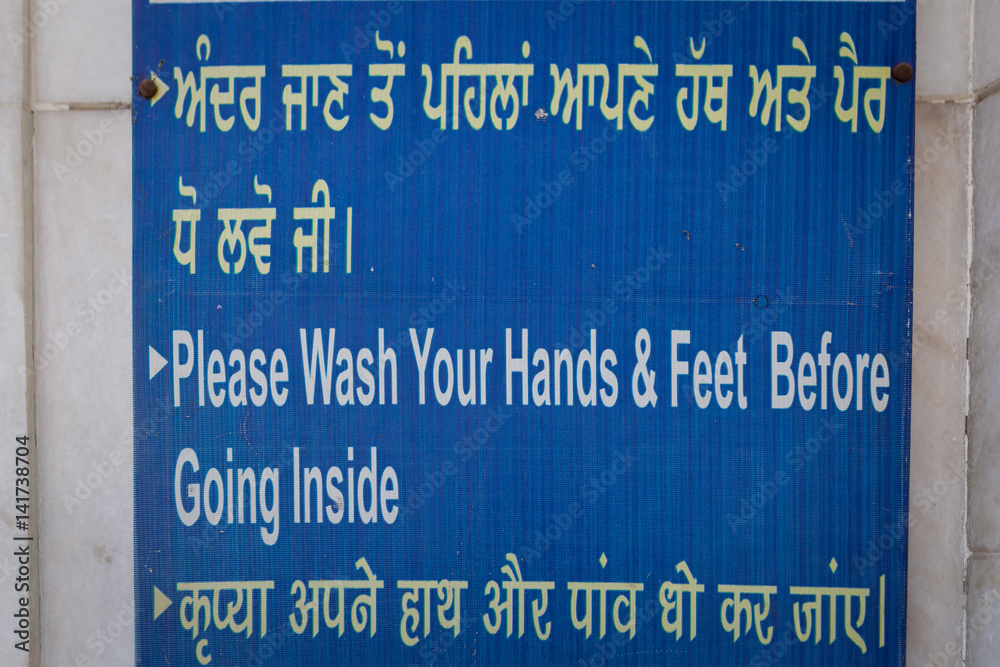 Information board at the entrance to the Golden Tempe in Amritsar, India: wash hands and feet