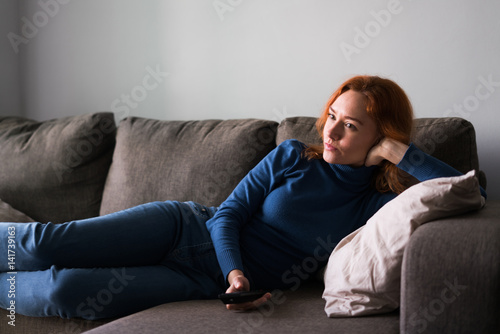 Woman on couch surfing channels photo