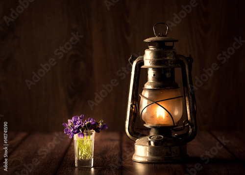 Spring concept with violet and oil lamp on wooden table