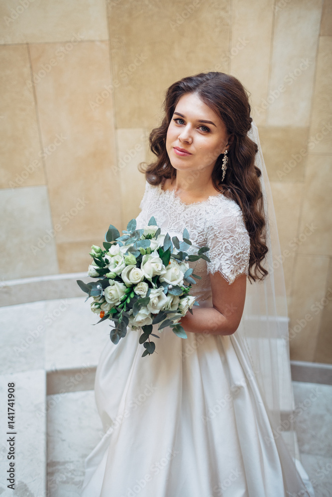 Look from above at charming bride with brown curls holding white wedding bouquet Look from above at charming bride with brown curls holding white wedding bouquet