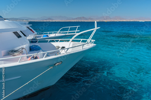 View at the coral sea and white yacht. Perfect place for snorkeling. Summer vacation at sea with turquoise clear water.