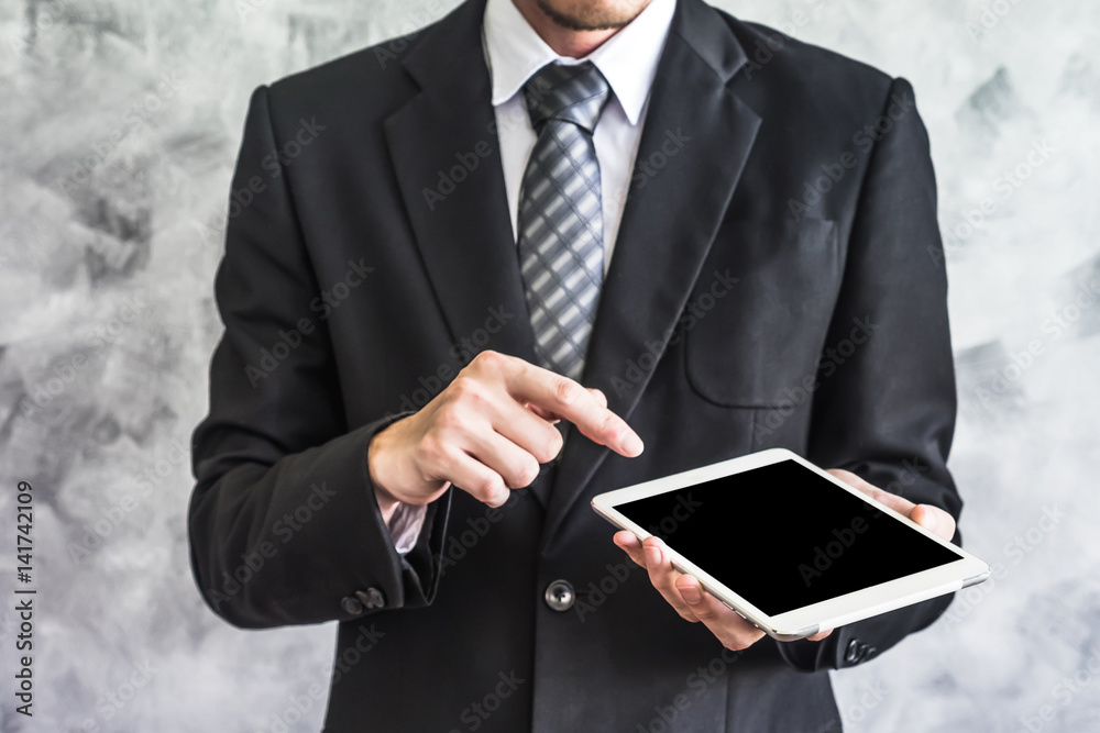 Close up of businessman holding tablet device on grunge background. Close up of businessman holding tablet device on grunge background.
