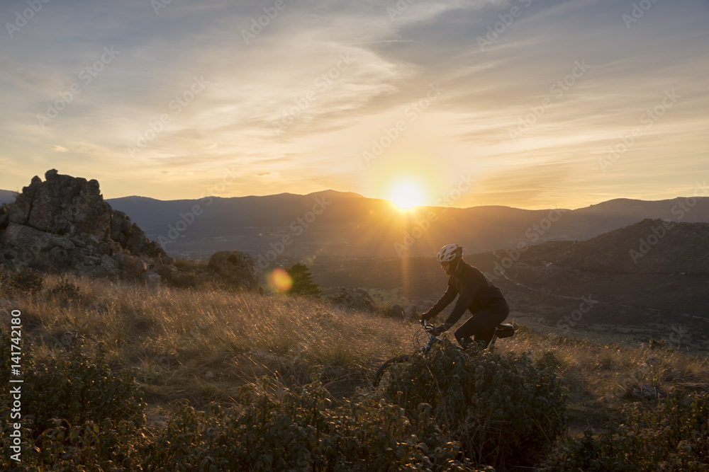 Cyclist on the mountain at sunset