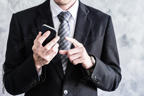 Close up of businessman using smart phone on grunge background.