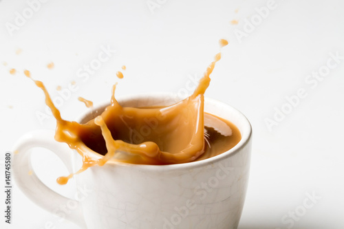 Cup of splashing coffee on white background