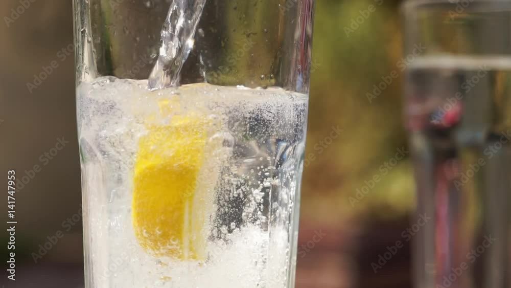Pouring sparkling water, tonic in a glass beaker. Container filled with sparkling water placed on table. Slow motion full HD video footage 1920x1080