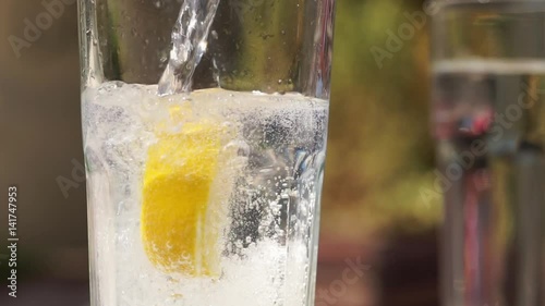 Pouring sparkling water, tonic in a glass beaker. Container filled with sparkling water placed on table. Slow motion full HD video footage 1920x1080