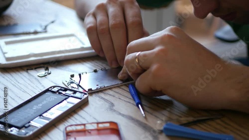 Master repairing broken phone, stares, collects small parts, which are on the table, connects ditali press. 3840x2160. 4k photo