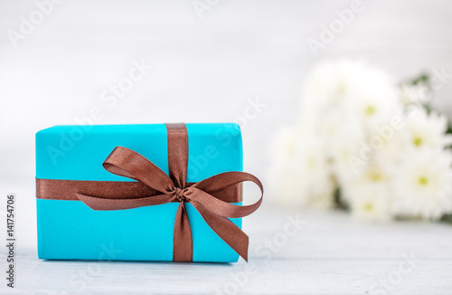 Blue box with a gift and flowers. The concept of Mother's Day, birthday, March 8.