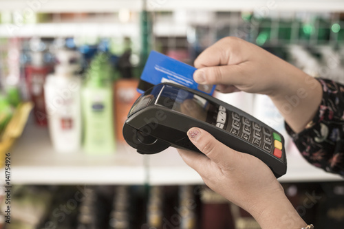 Hands carrying credit card machine reader background is supermarket shelves