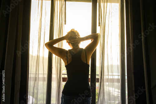 Woman stand on the door while looking out of the window - back of silhouette woman