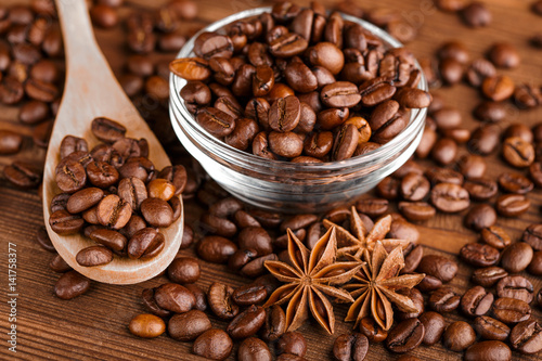 Coffee beans and cinnamon on a background of burlap. Roasted coffee beans background close up. Coffee beans pile from top with copy space for text. Seasoning. Spice. Cinnamon. Badian. Coffee house.