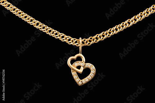 Gold chain and pendant in the shape of heart on a black background