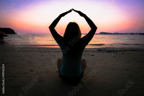 Silhouette woman yoga on the beach over the sunset