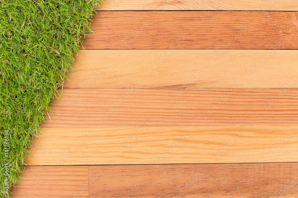 Synthetic green grass and wooden wall, natural background.