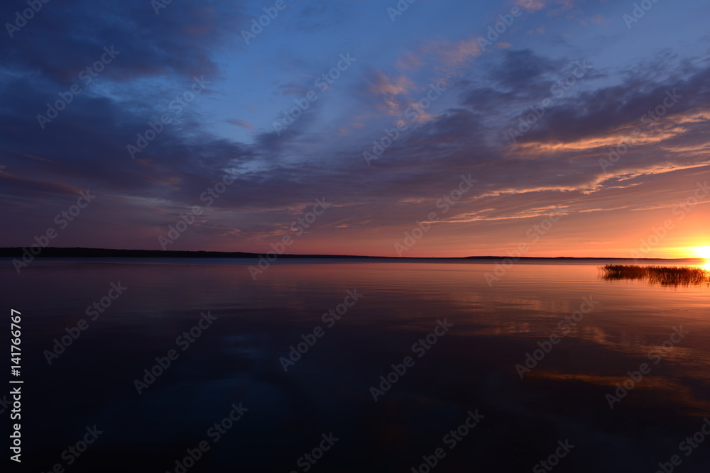 Brightly red halo of sunset near the surface of the water under a blue sky