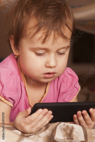 Social Media addiction. beautiful baby girl  holding phone (psychological problems, media mania, education)