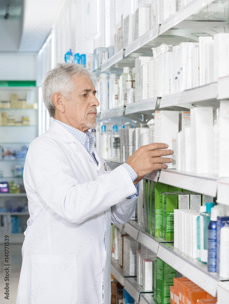 Pharmacist Arranging Medicines On Shelf