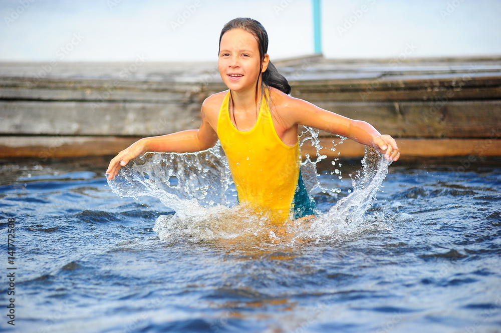 Little girl in a yellow bathing suit playing in the water Stock Photo