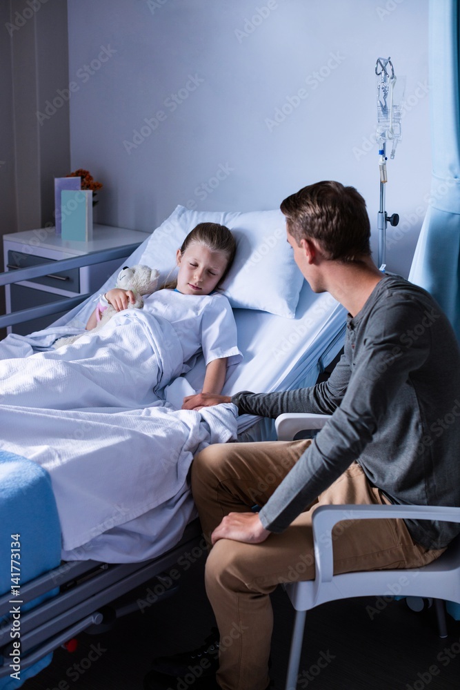 Father sitting beside her daughter lying on a hospital bed Father sitting beside her daughter lying on a hospital bed
