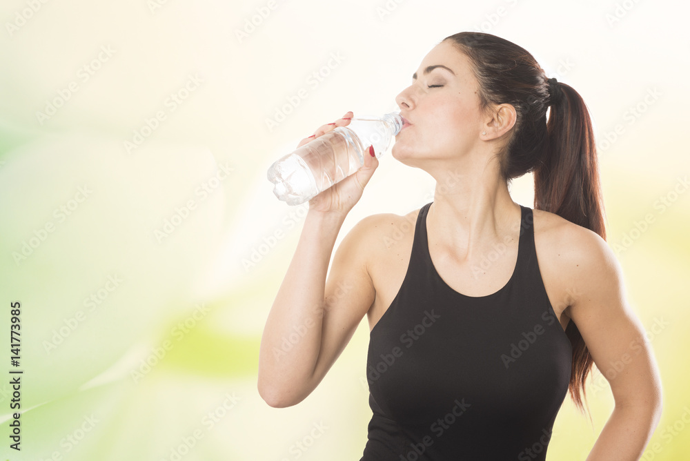 A young beautiful woman drinking from a bottle of water A young beautiful woman drinking from a bottle of water