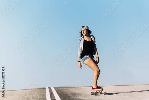 Beautiful skater woman riding on her longboard. photo