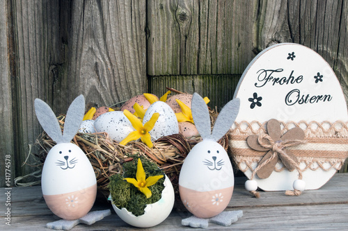 Osterkarte mit Text Frohe Ostern mit Osterhasen und Ostereier rustikal vor Holz