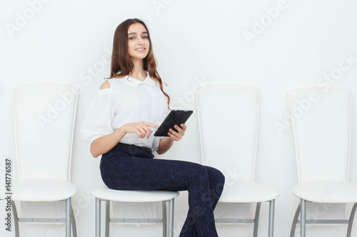 Young girl sitting on a chair and using a tablet