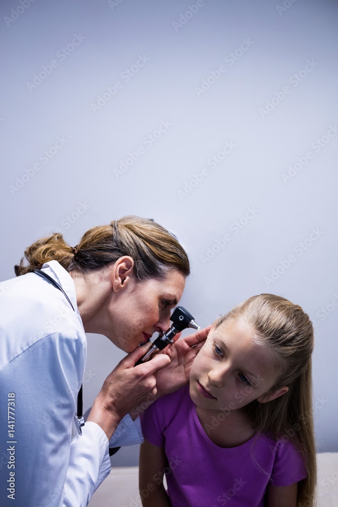 Female doctor examining patient ear with otoscope Female doctor examining patient ear with otoscope